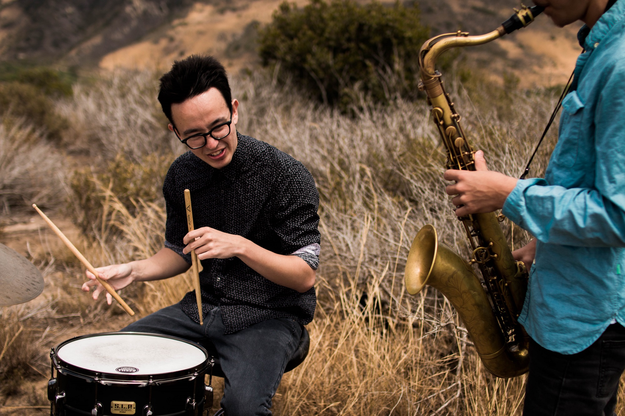 Photo of men playing drum and sax in a field by Cole Hutson